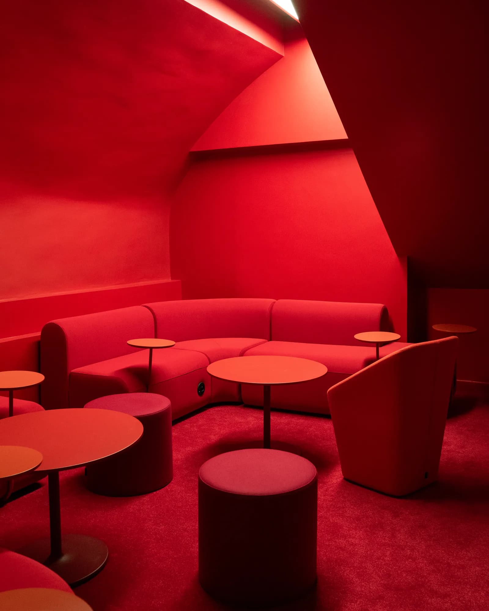 Salon monochrome rouge — banquette et tables basses, lieu UFO.