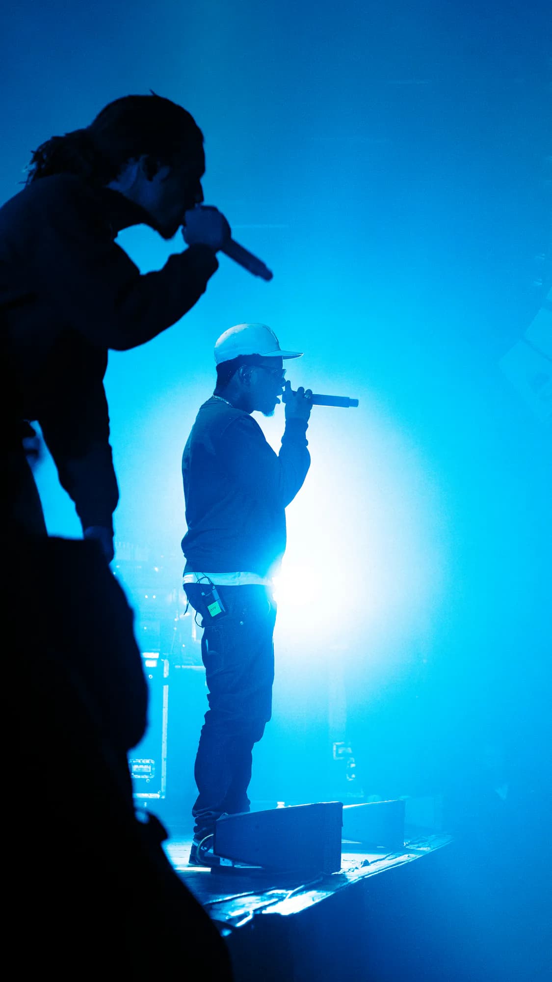 Concert de Léto. — deux artistes en silhouette devant un mur de lumière bleue