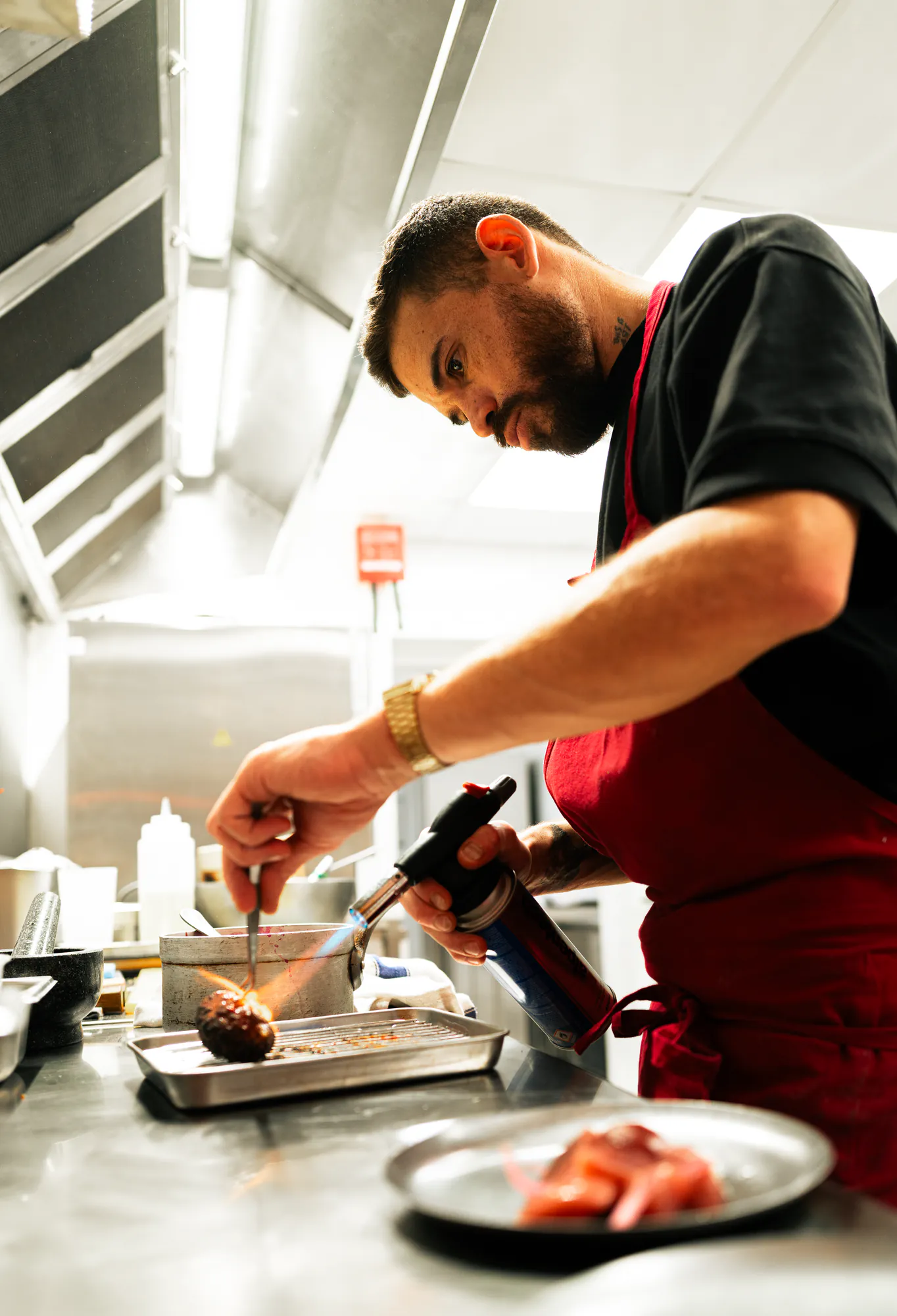 Chef au chalumeau en cuisine, tablier rouge — restaurant UFO.